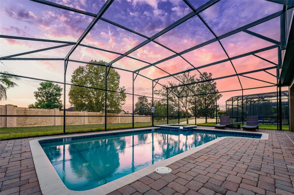 A screened-in swimming pool and spa are surrounded by a paved patio at sunset — 1496 MOON VALLEY DRIVE, DAVENPORT, FL