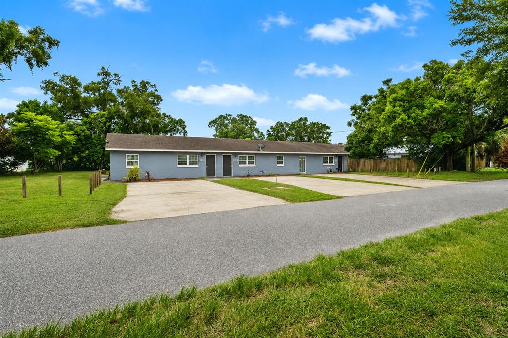 A single-story gray duplex with two concrete parking pads sits on a grassy lot — 5214 JOSEPHINE STREET, ORLANDO, FL