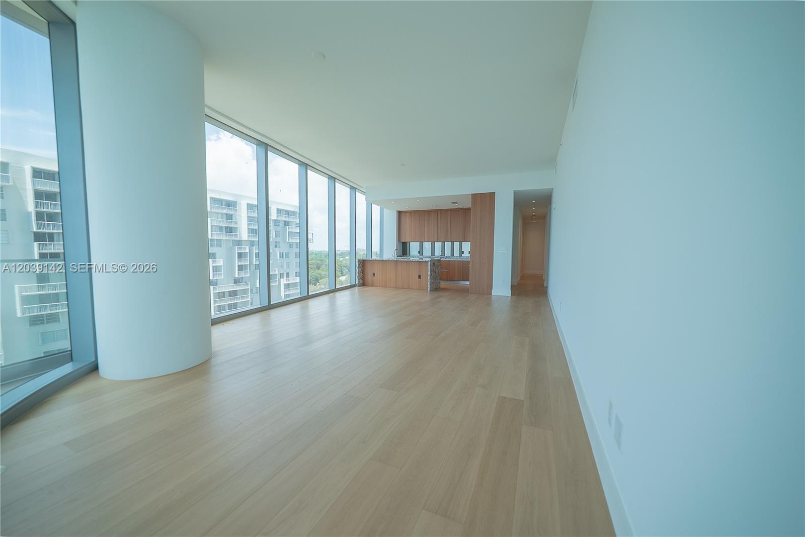 An open-concept living area features light wood flooring, floor-to-ceiling windows, and a modern kitchen — 175 SE 25th Rd # 702, Miami FL 33129, MIAMI, FL