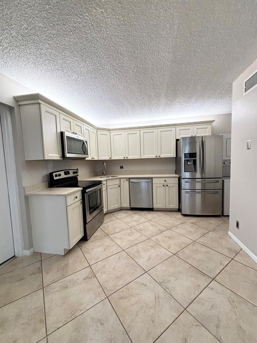 A kitchen with white cabinets, stainless steel appliances, and light-colored tile flooring — 203 Foxtail Drive # F1, FL 33415, FL