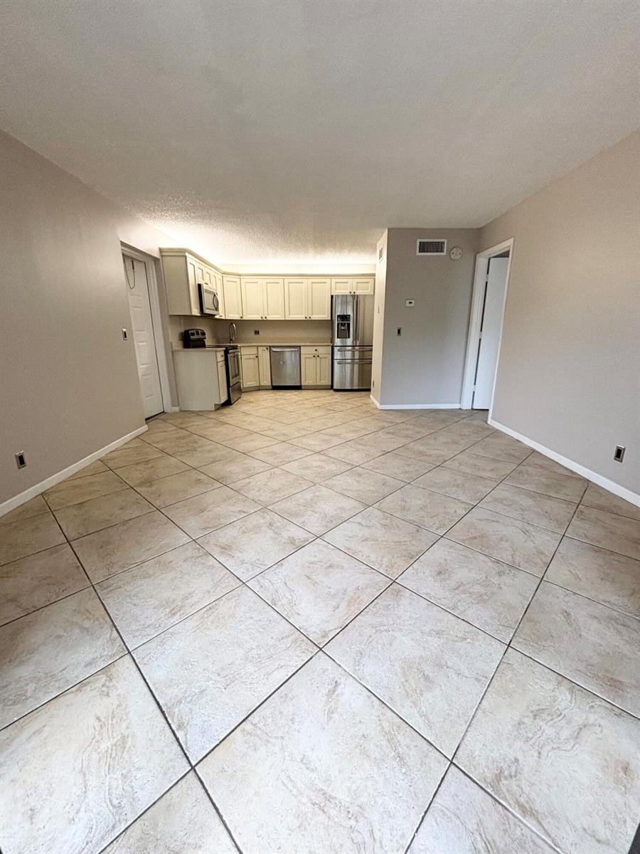 A kitchen with light-colored cabinets and stainless steel appliances features tile flooring set diagonally — 203 Foxtail Drive # F1, FL 33415, FL