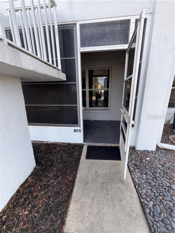 An exterior view of a ground-level apartment entrance with a screen door and concrete walkway — 805 SE MAYO DRIVE UNIT 805, CRYSTAL RIVER, FL