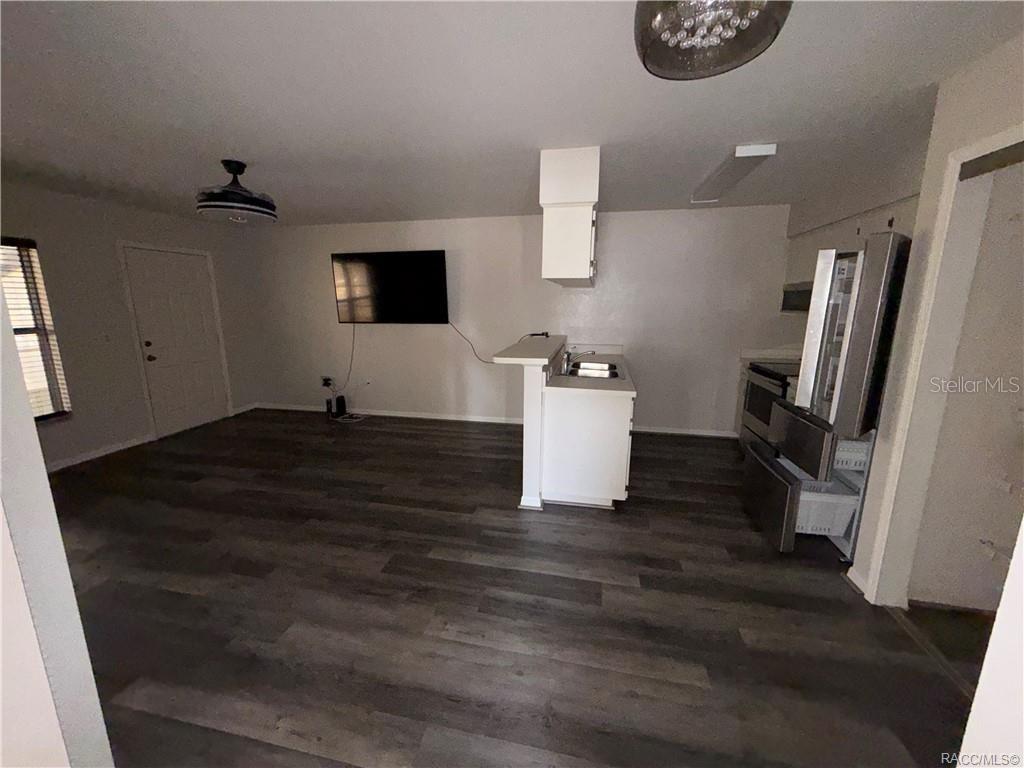 An open-concept living area features wood-look flooring, a kitchen island, and a wall-mounted television — 805 SE MAYO DRIVE UNIT 805, CRYSTAL RIVER, FL