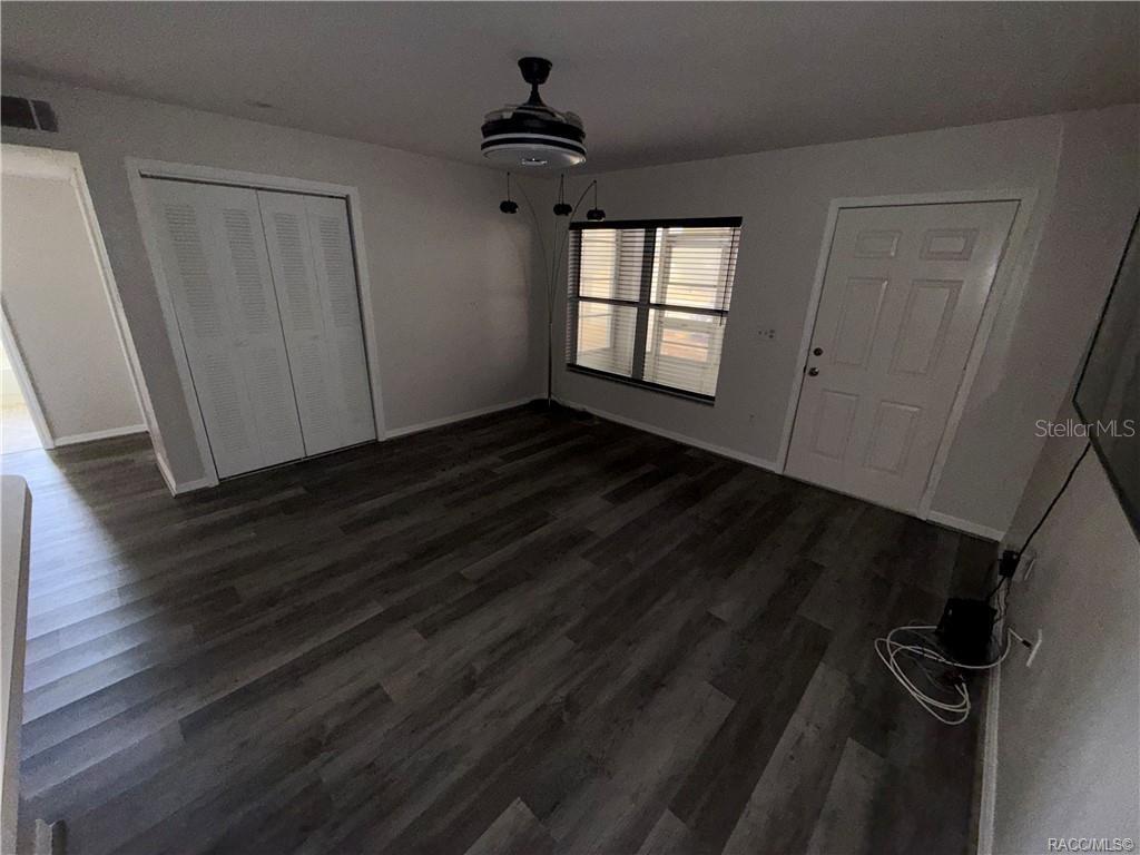 A room with gray wood-look flooring, a ceiling fan, a window, and a white door — 805 SE MAYO DRIVE UNIT 805, CRYSTAL RIVER, FL