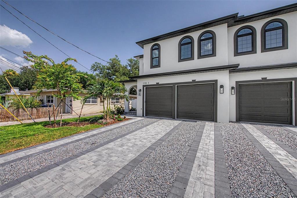 A modern two-story duplex with a paver driveway and three garage doors — 110 S ARRAWANA AVENUE UNIT 1, TAMPA, FL