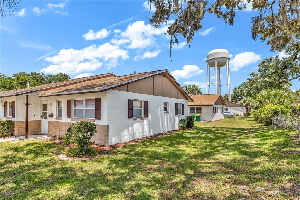 A one-story residential building with white block walls stands near a large water tower — 706 E MINNESOTA AVENUE UNIT C, DELAND, FL