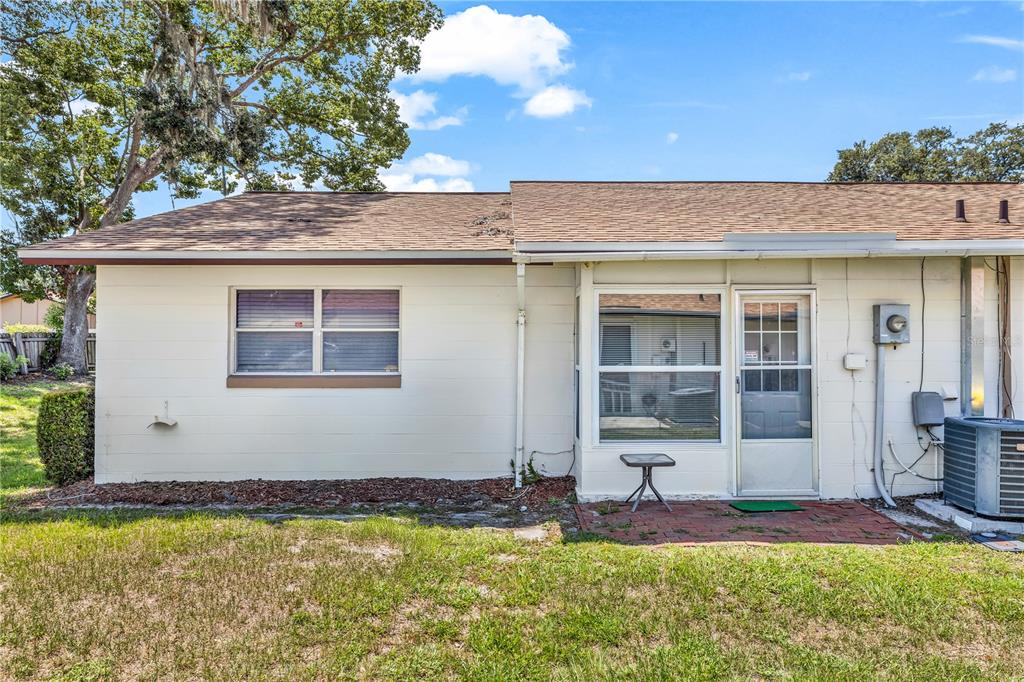 The exterior of a single-story home features a white concrete block wall and a patio — 706 E MINNESOTA AVENUE UNIT C, DELAND, FL