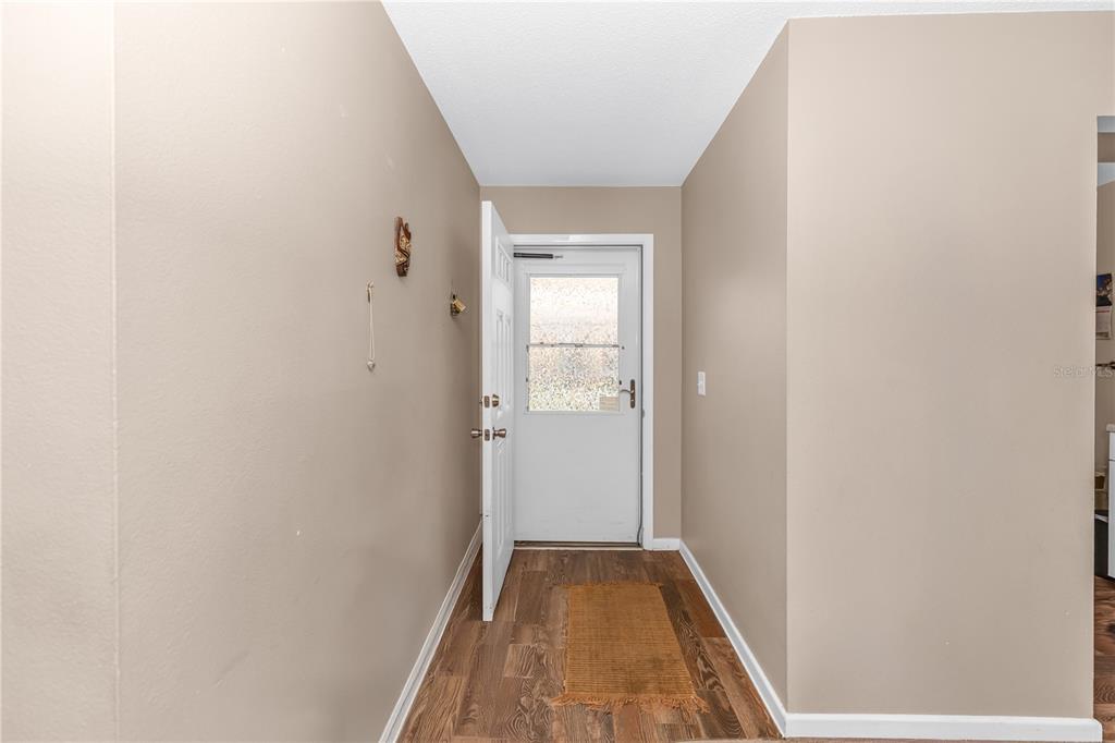 An entryway features light brown walls, wood-look flooring, and a white door with glass — 706 E MINNESOTA AVENUE UNIT C, DELAND, FL