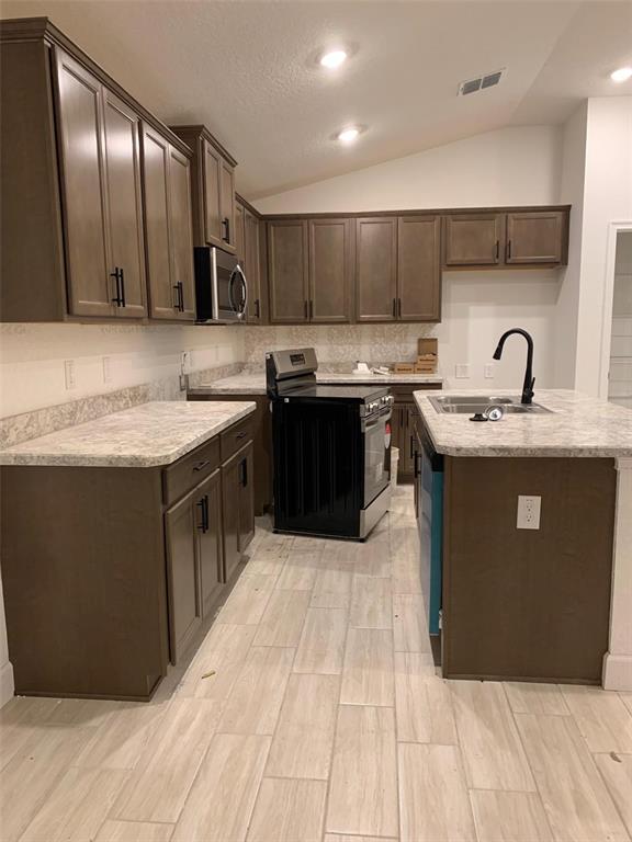 A kitchen features brown cabinets, light countertops, a black stove, and light-colored tile flooring — 2137 W SAY DRIVE, DUNNELLON, FL