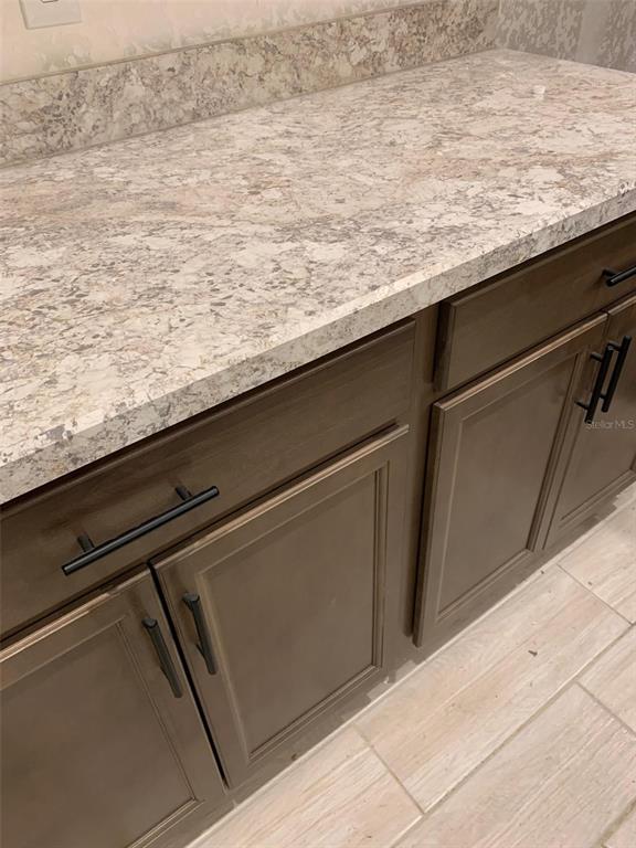 A bathroom vanity features dark wood cabinets, black hardware, and a light-colored stone countertop — 2137 W SAY DRIVE, DUNNELLON, FL