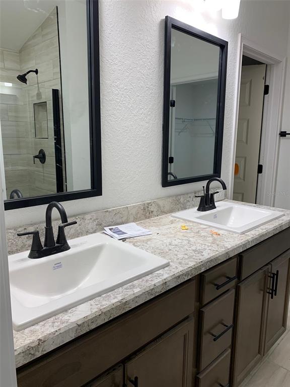 A double vanity bathroom features dark wood cabinets, light stone countertops, and black fixtures — 2137 W SAY DRIVE, DUNNELLON, FL