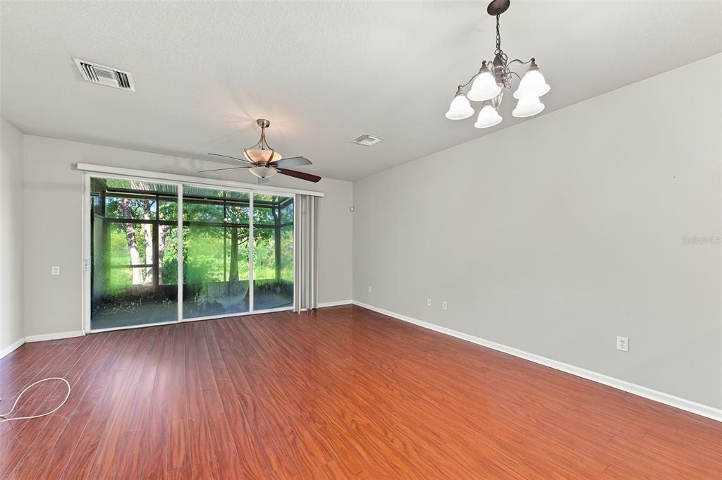 A living room features wood-look flooring, a ceiling fan, a chandelier, and sliding glass doors — 2109 WILD GRAPE PLACE, RIVERVIEW, FL