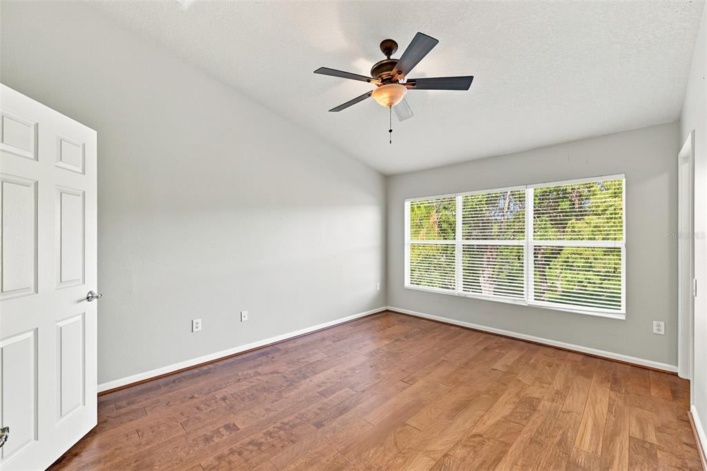 An empty bedroom with light gray walls, wood flooring, a ceiling fan, and large windows — 2109 WILD GRAPE PLACE, RIVERVIEW, FL