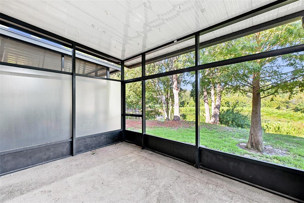 A screened-in porch with a concrete floor, white ceiling, and views of trees and grass — 2109 WILD GRAPE PLACE, RIVERVIEW, FL