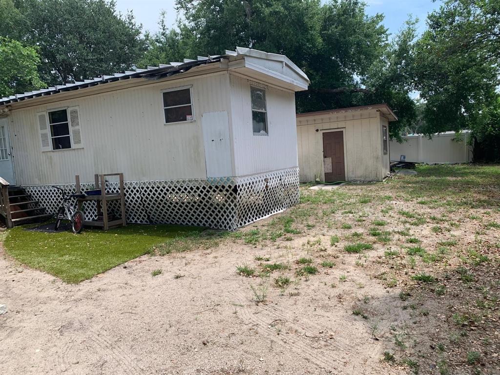 A mobile home with white siding and lattice skirting sits next to a small shed — 10803 TUCKAWAY DRIVE, THONOTOSASSA, FL