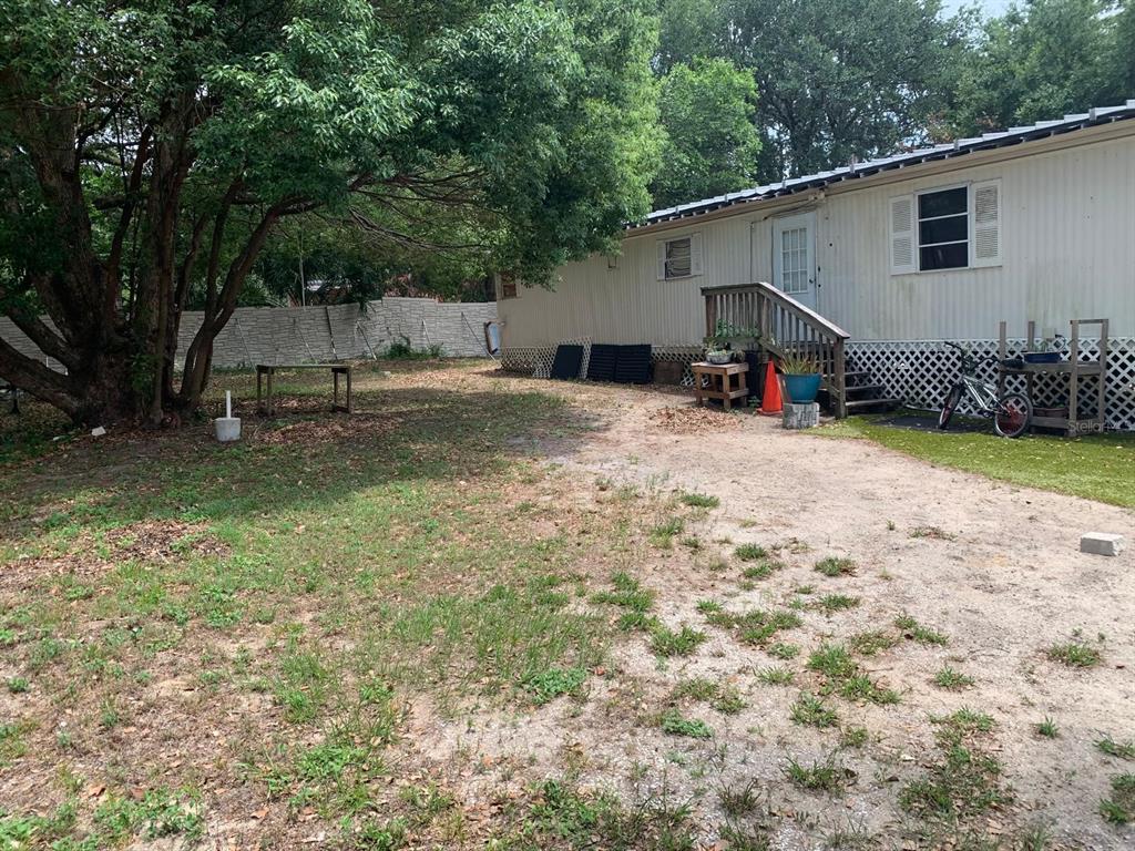 A side view of a mobile home with a wooden staircase and a large tree — 10803 TUCKAWAY DRIVE, THONOTOSASSA, FL