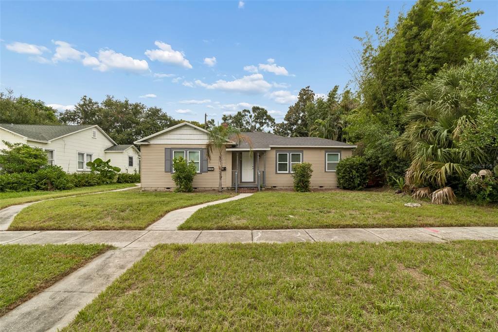 A single-story house with tan siding and a front porch sits behind a grassy lawn — 3601 6TH AVENUE N, ST PETERSBURG, FL