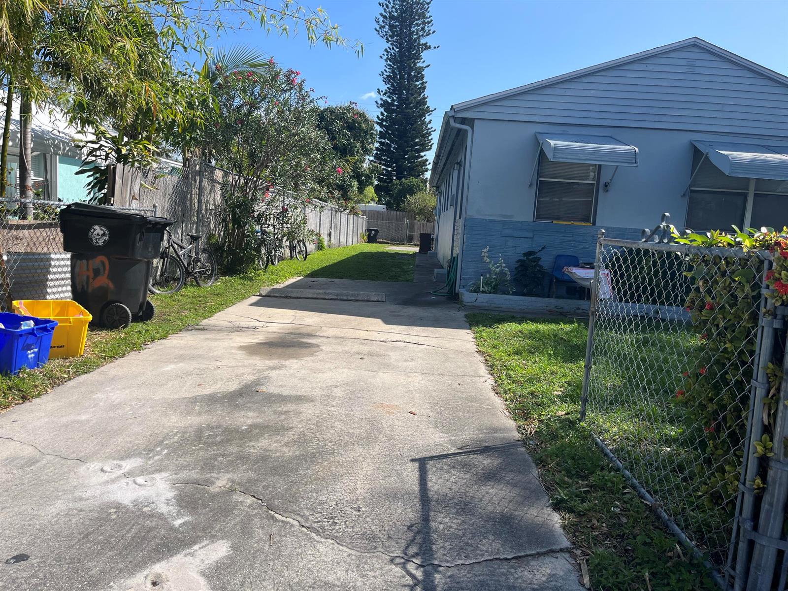 A concrete driveway leads alongside a light blue house with a chain-link fence — 530 S C Street W, FL 33460, FL