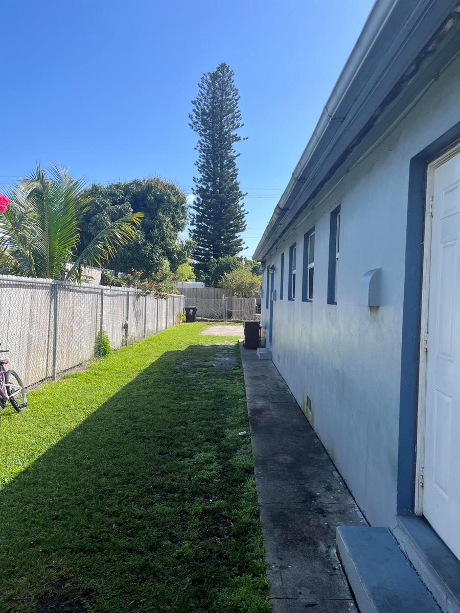 A side yard features a concrete walkway along a blue house and a chain-link fence — 530 S C Street W, FL 33460, FL