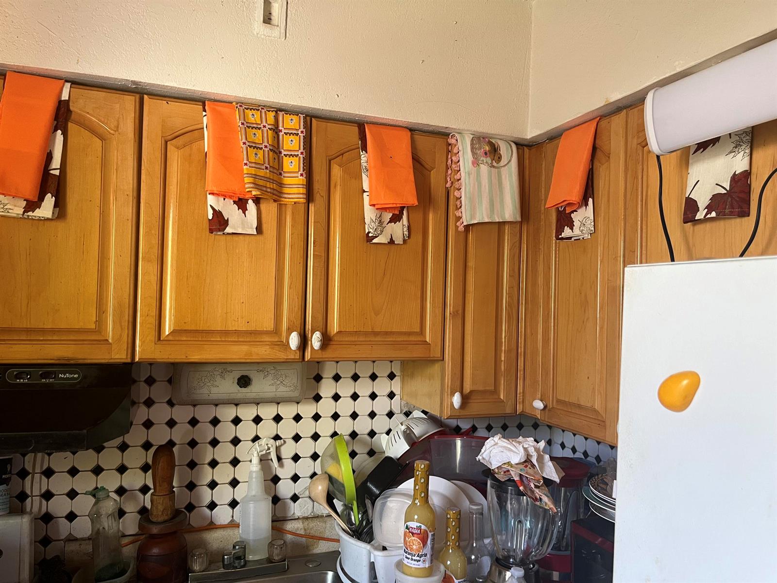A kitchen features wooden cabinets, a black and white tiled backsplash, and hanging decorative towels — 530 S C Street W, FL 33460, FL
