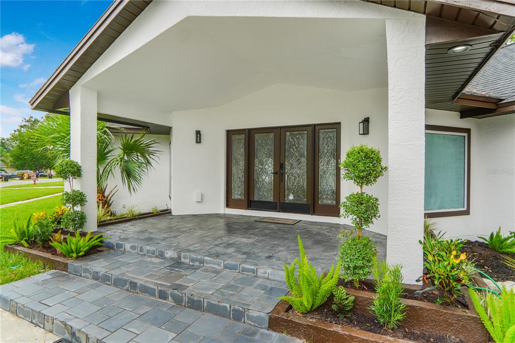 A covered stone porch leads to a double front door with decorative glass panels — 2286 LAKE FRANCIS DRIVE, APOPKA, FL