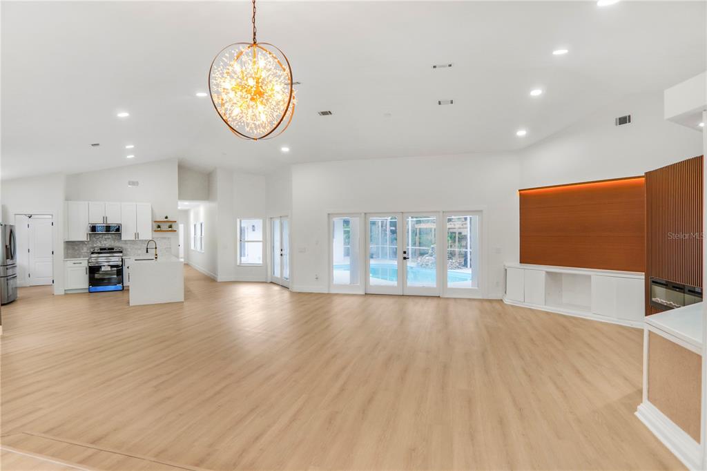 An open-concept living area features light wood flooring, a modern chandelier, and a kitchen — 2286 LAKE FRANCIS DRIVE, APOPKA, FL