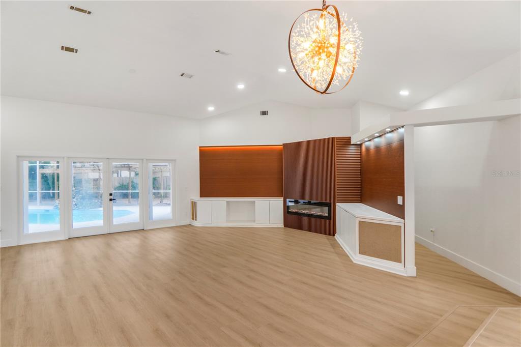 A living room features light wood flooring, a modern fireplace, wood-paneled walls, and glass doors — 2286 LAKE FRANCIS DRIVE, APOPKA, FL