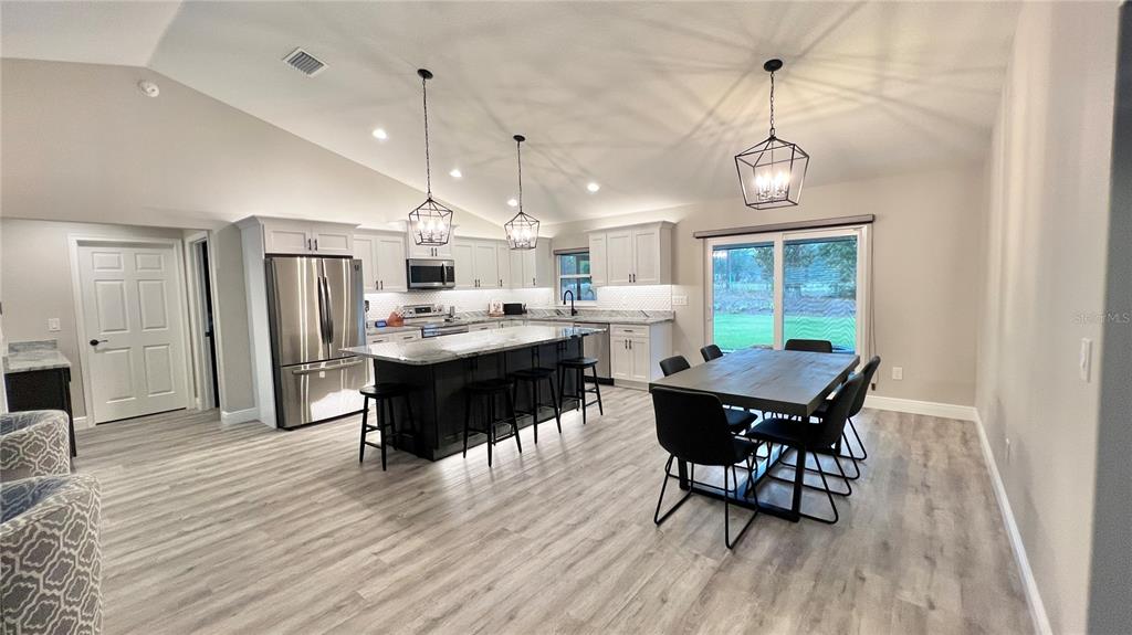 A modern kitchen features a large island, stainless steel appliances, and a dining area — 6944 SW 179TH COURT ROAD, DUNNELLON, FL