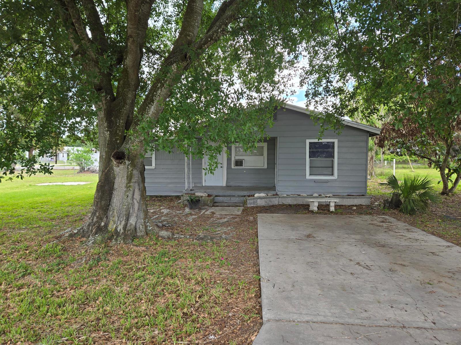 A gray, single-story house with a concrete driveway and a large tree in the yard — 408 NW 10th Avenue, Okeechobee FL 34974, OKEECHOBEE, FL
