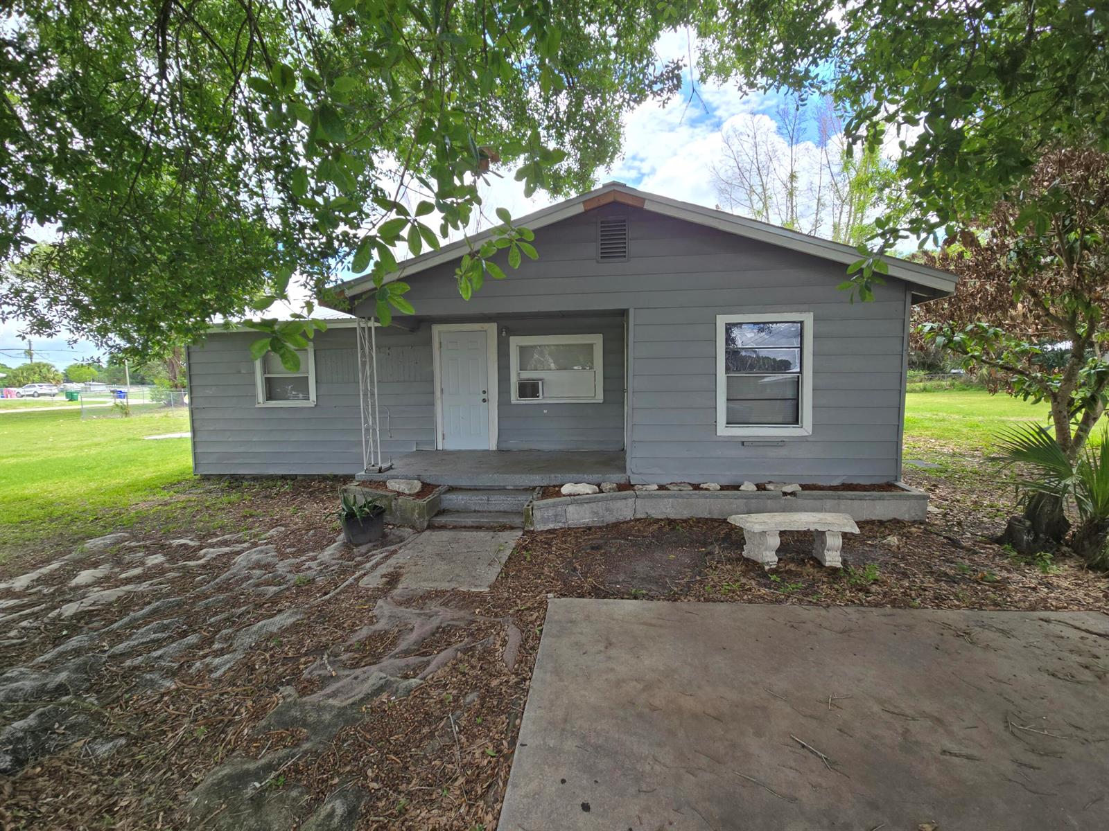 A gray, single-story house with a front porch, white trim, and a concrete driveway — 408 NW 10th Avenue, Okeechobee FL 34974, OKEECHOBEE, FL