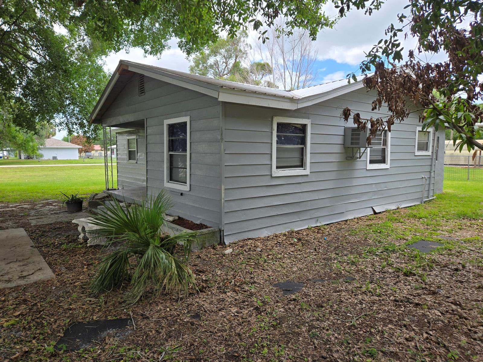 A gray, single-story house with horizontal siding and a metal roof sits on a lot — 408 NW 10th Avenue, Okeechobee FL 34974, OKEECHOBEE, FL
