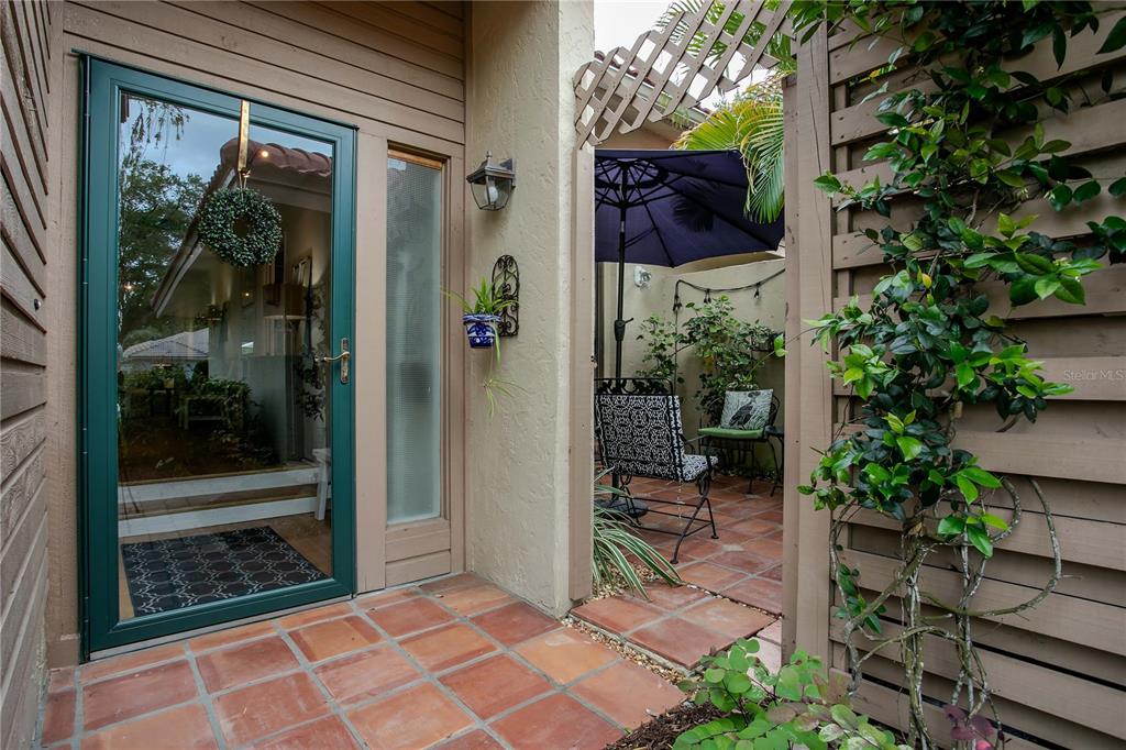 A tiled entryway leads to a glass front door and an adjacent outdoor patio area — 1732 KESTRAL PARK WAY S UNIT 43, SARASOTA, FL