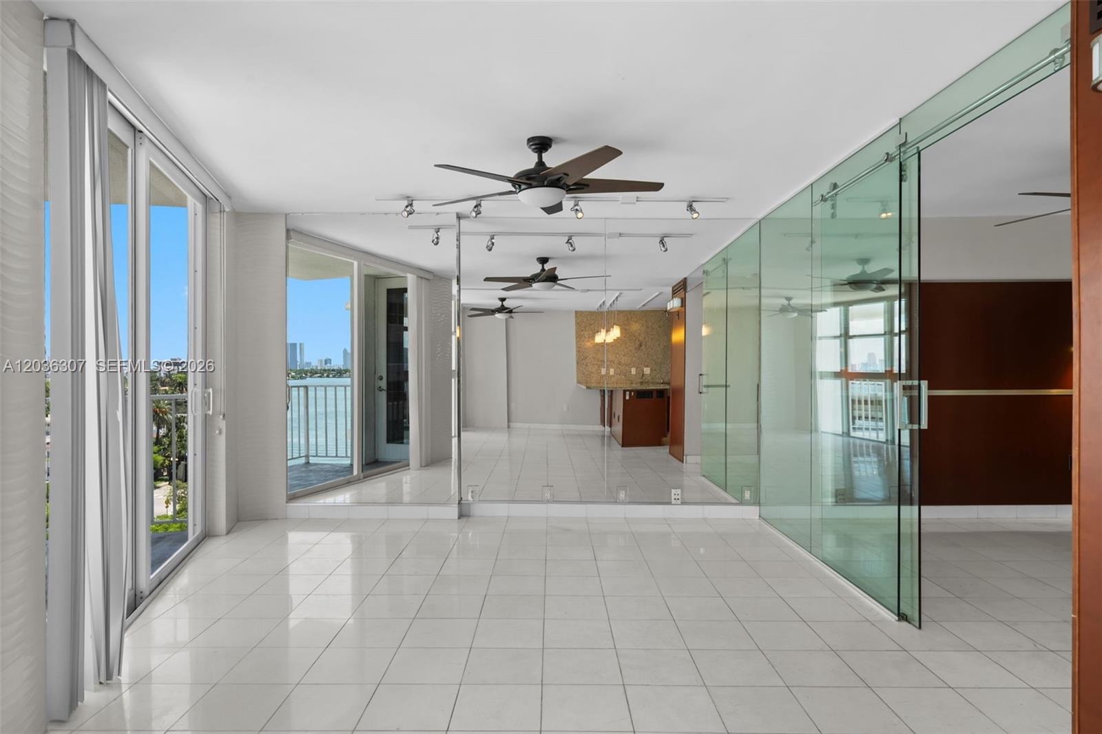 A bright room features white tile floors, mirrored walls, glass partitions, and a balcony view — 1228 West Ave # 604, Miami Beach FL 33139, MIAMI BEACH, FL