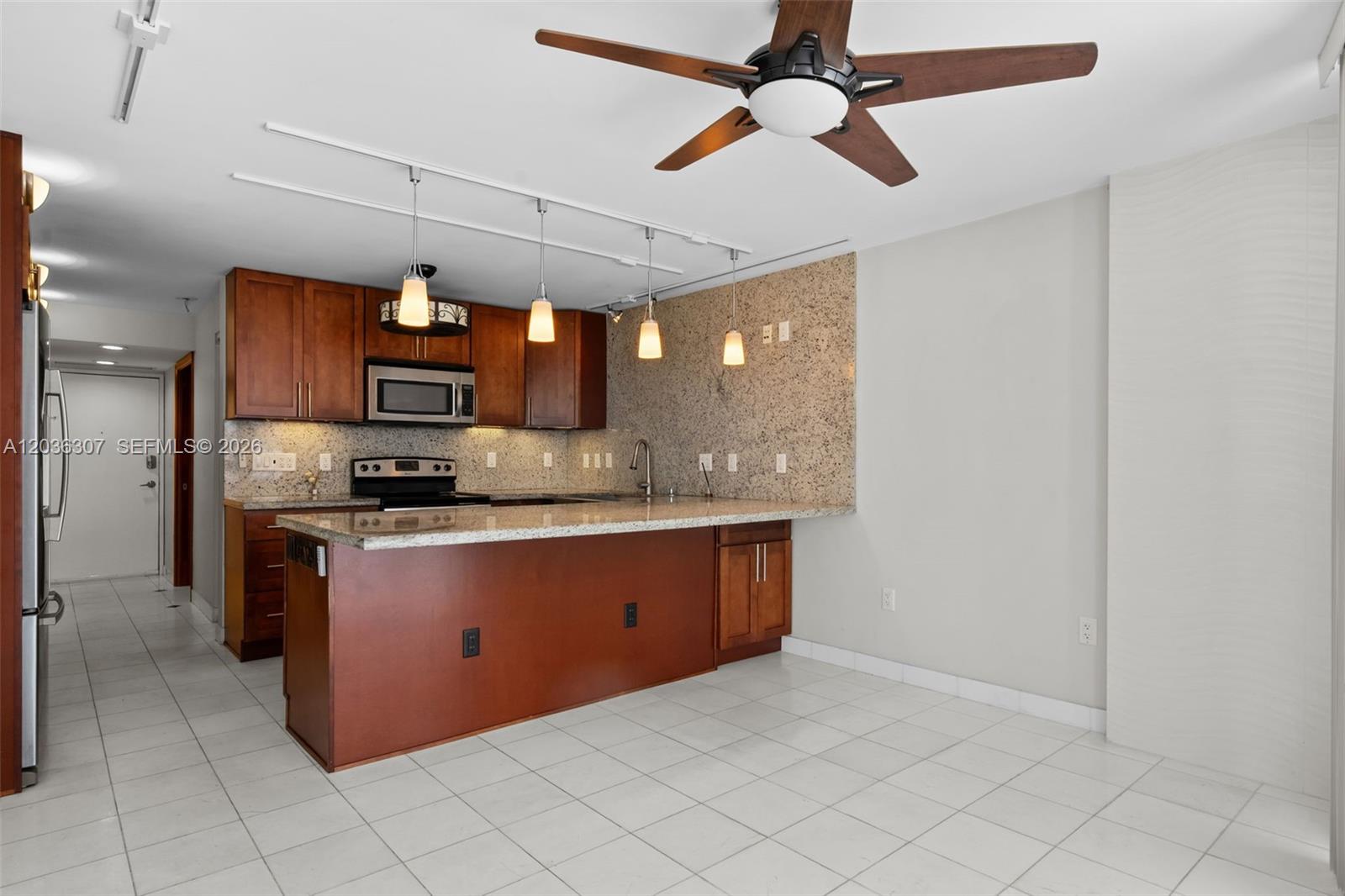 A kitchen features wood cabinets, granite countertops, a breakfast bar, and a ceiling fan — 1228 West Ave # 604, Miami Beach FL 33139, MIAMI BEACH, FL