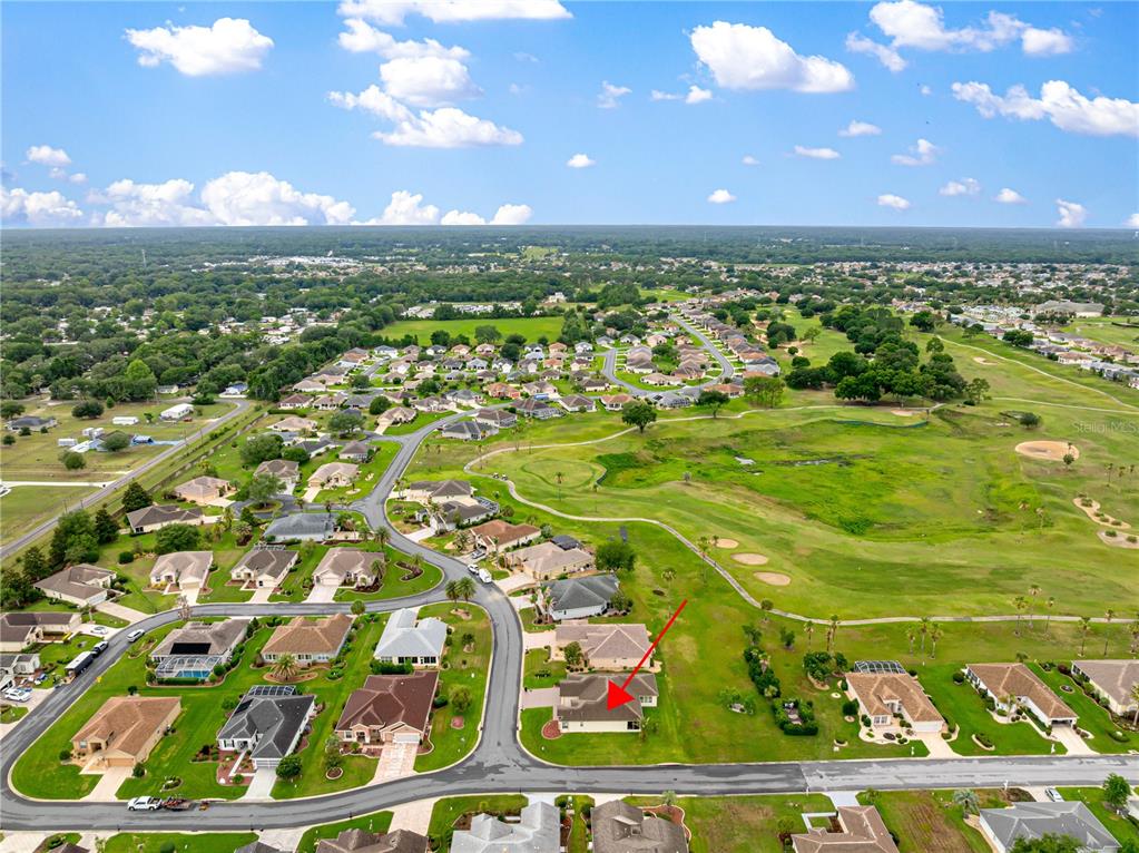 An aerial view shows a residential neighborhood with a red arrow pointing to a house — 9687 SE 137TH STREET ROAD, SUMMERFIELD, FL