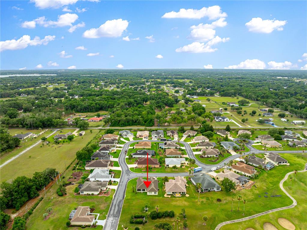 An aerial view shows a suburban neighborhood with a red arrow pointing to a house — 9687 SE 137TH STREET ROAD, SUMMERFIELD, FL
