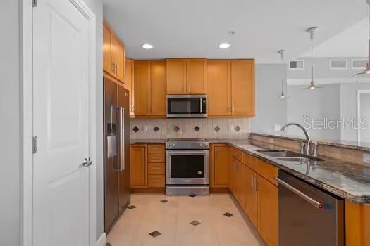 A kitchen features light wood cabinets, stainless steel appliances, and a granite countertop with a sink — 101 S EOLA DRIVE UNIT 1203, ORLANDO, FL