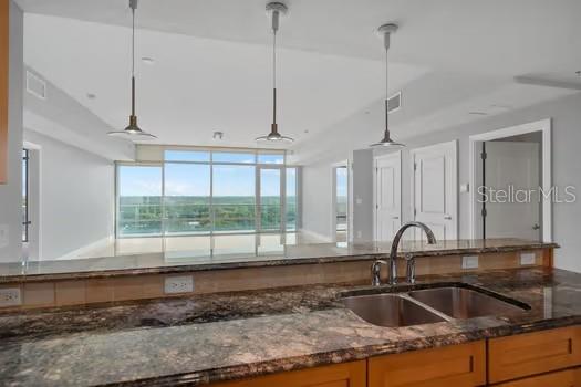 A kitchen island with a granite countertop and sink overlooks a living area with floor-to-ceiling windows — 101 S EOLA DRIVE UNIT 1203, ORLANDO, FL