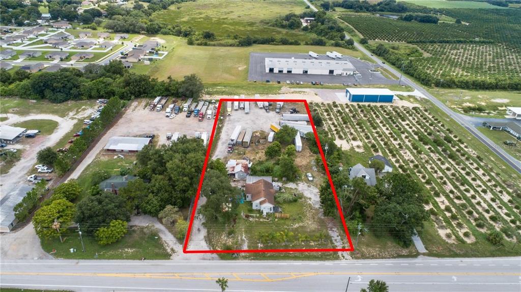 An aerial view shows a rectangular property with a house, outbuildings, and parked semi-trucks — 802 SCENIC HIGHWAY N, LAKE HAMILTON, FL