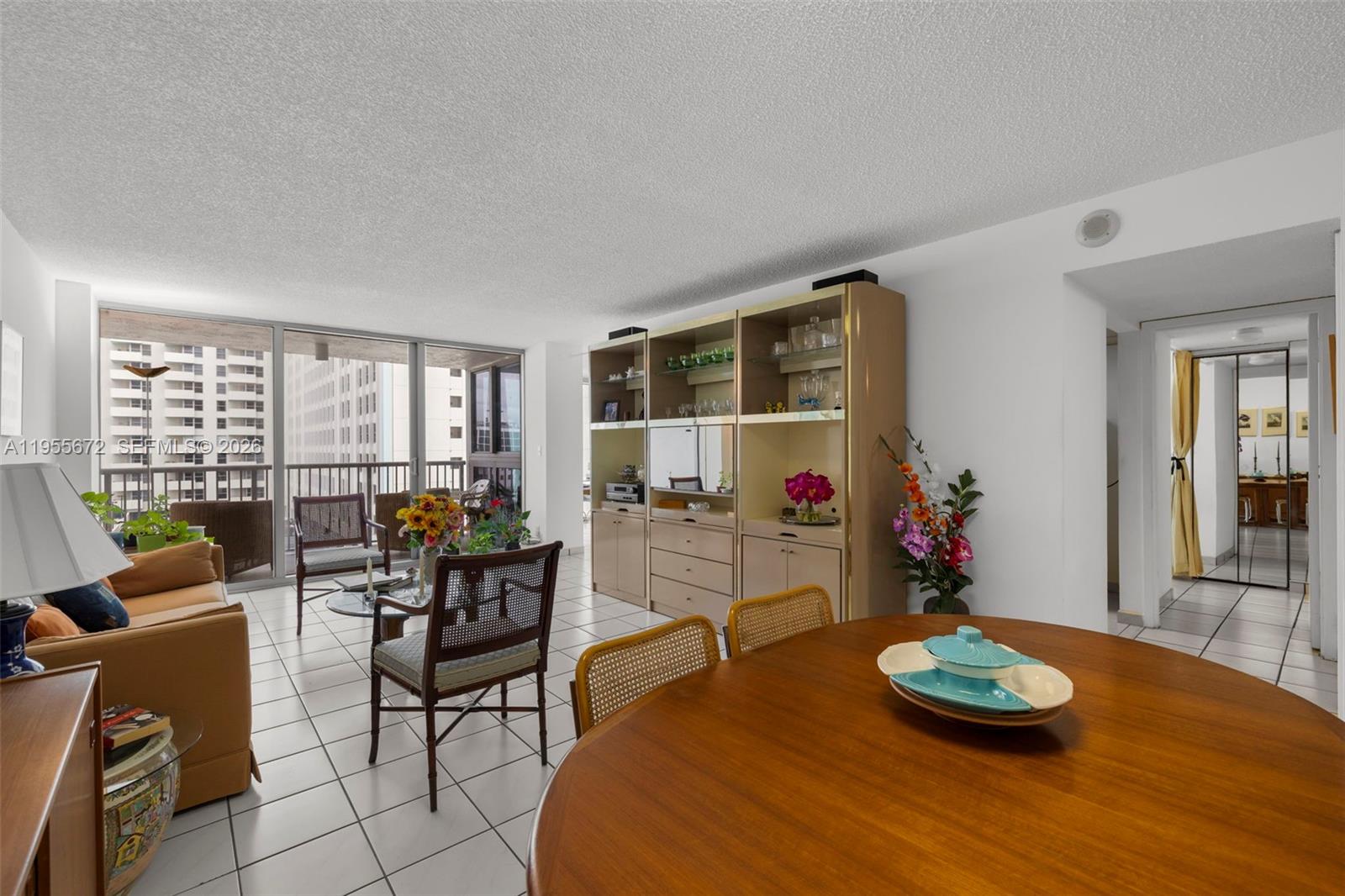 A living and dining area features tile floors, a large wall unit, and balcony access — 2655 Collins Ave # 707, Miami Beach FL 33140, MIAMI BEACH, FL
