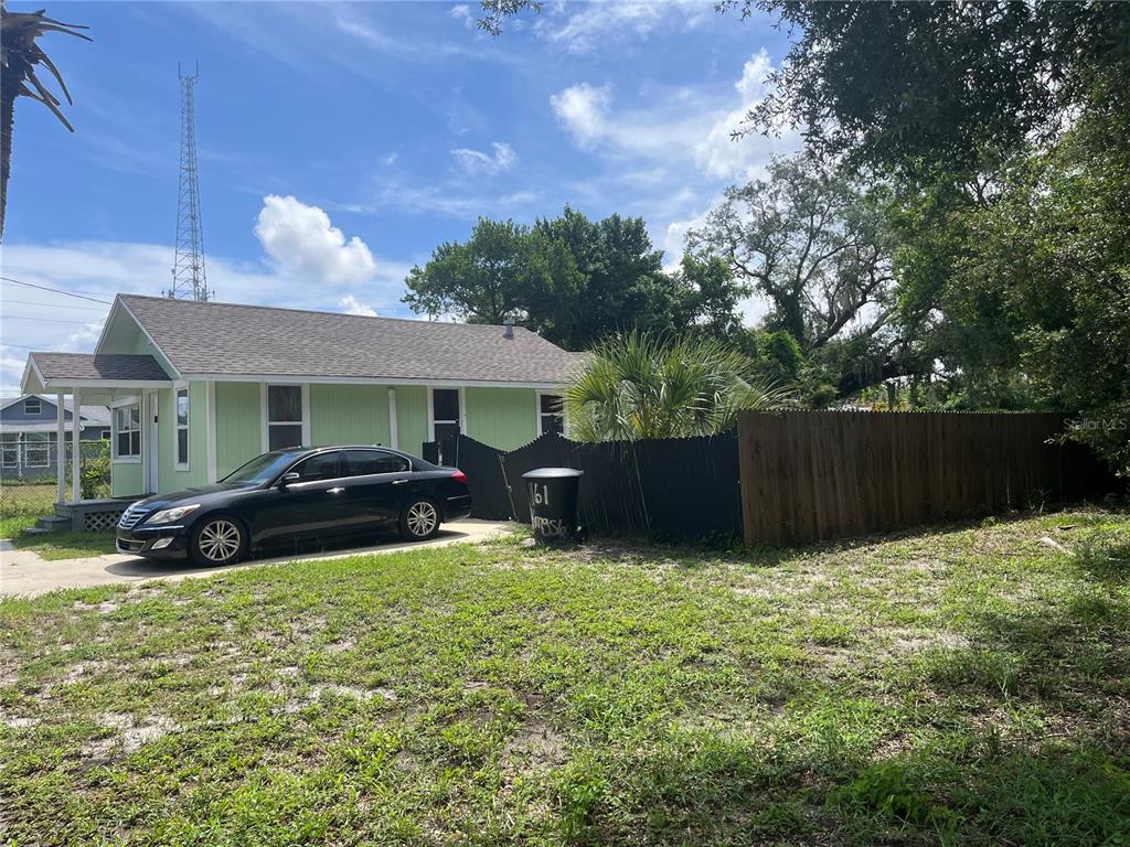 A light green house with a black fence and a parked car in the yard — 1161 KINGSLEY STREET, CLEARWATER, FL
