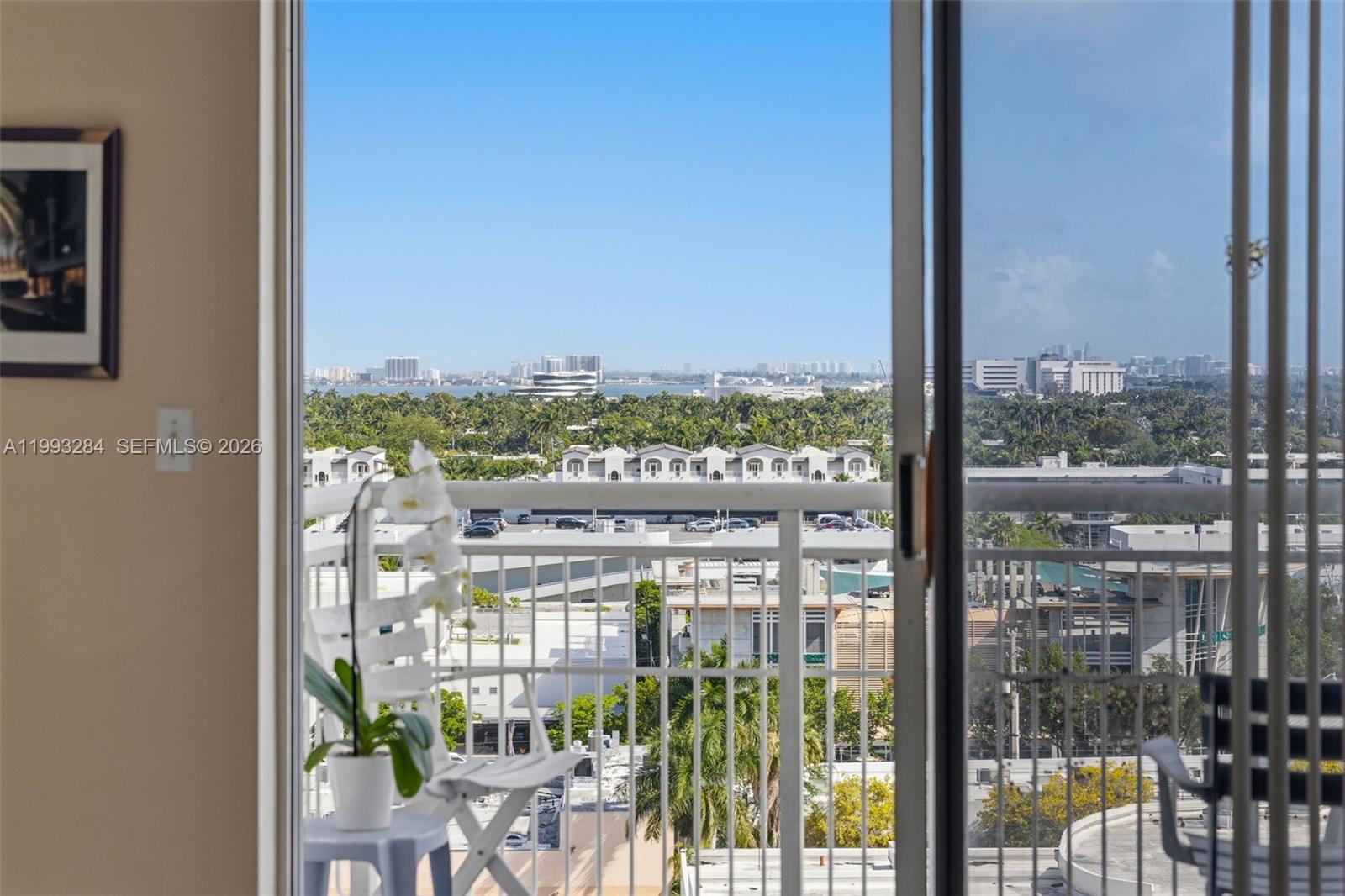 A view of a city skyline and lush trees from a balcony with a railing — 1688 West Ave # 1205, Miami Beach FL 33139, MIAMI BEACH, FL