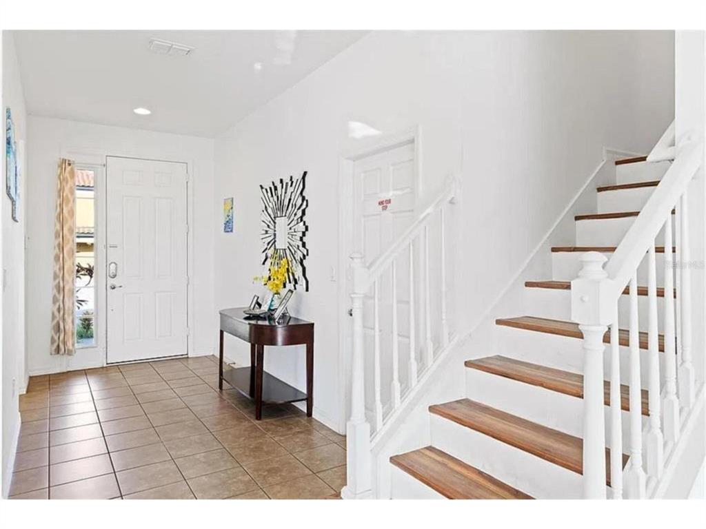An entryway with tile flooring, a white front door, a console table, and wooden stairs — 2654 ROSEMONT CIRCLE, DAVENPORT, FL