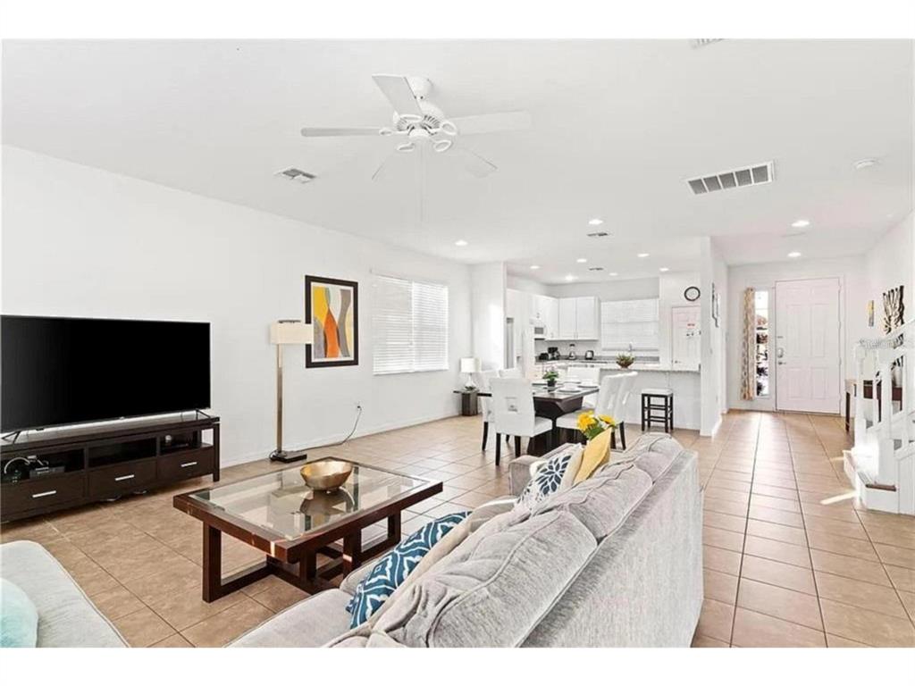 A living room with tile floors, a television, a coffee table, and an open kitchen — 2654 ROSEMONT CIRCLE, DAVENPORT, FL