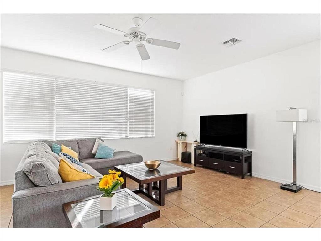 A living room with a gray sectional sofa, glass-topped coffee tables, and a television console — 2654 ROSEMONT CIRCLE, DAVENPORT, FL