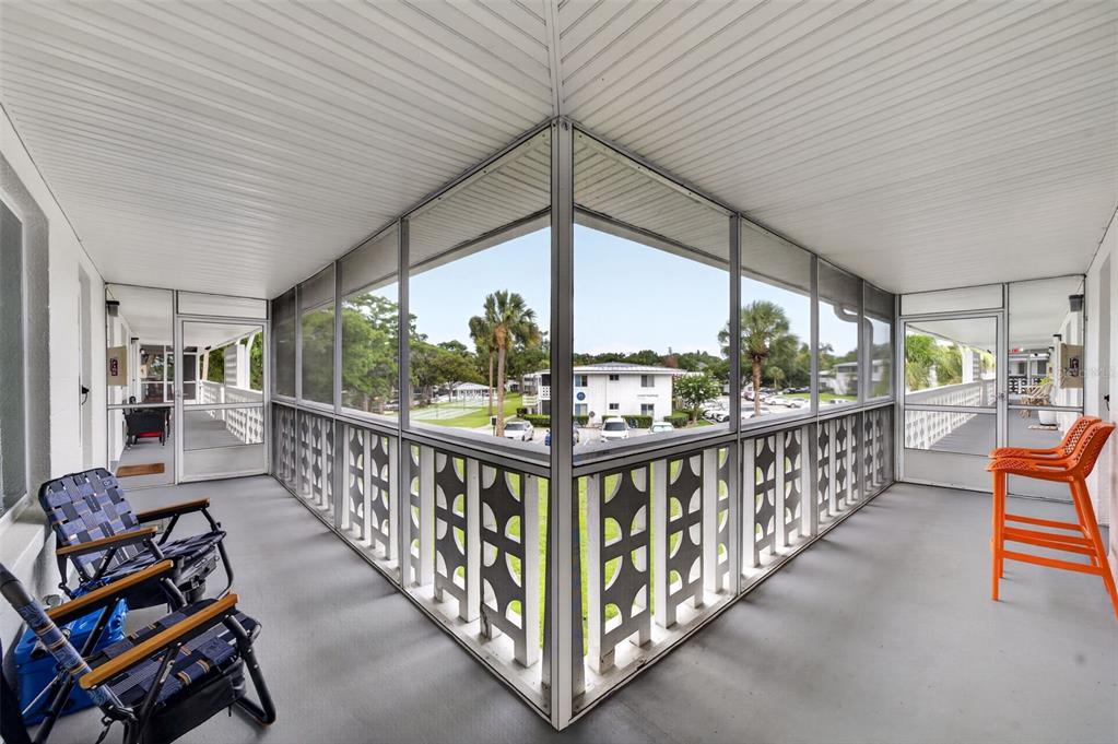 A screened-in balcony with grey flooring, white railings, and views of a parking lot — 1140 S ORLANDO AVENUE UNIT K15, MAITLAND, FL