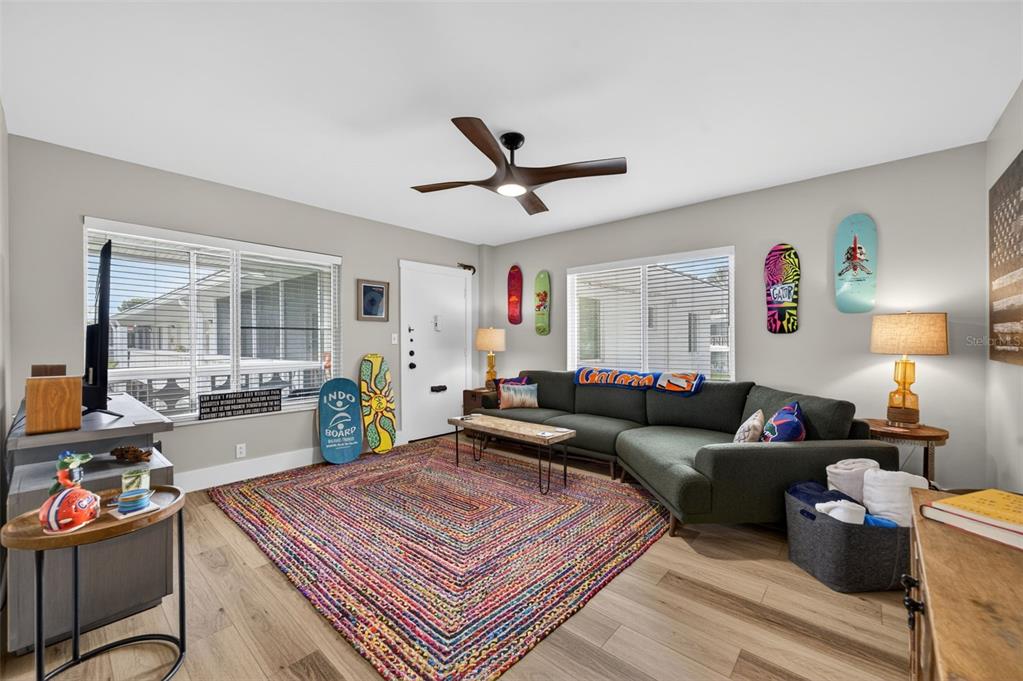 A living room features a sectional sofa, a colorful woven rug, and skateboard wall decor — 1140 S ORLANDO AVENUE UNIT K15, MAITLAND, FL