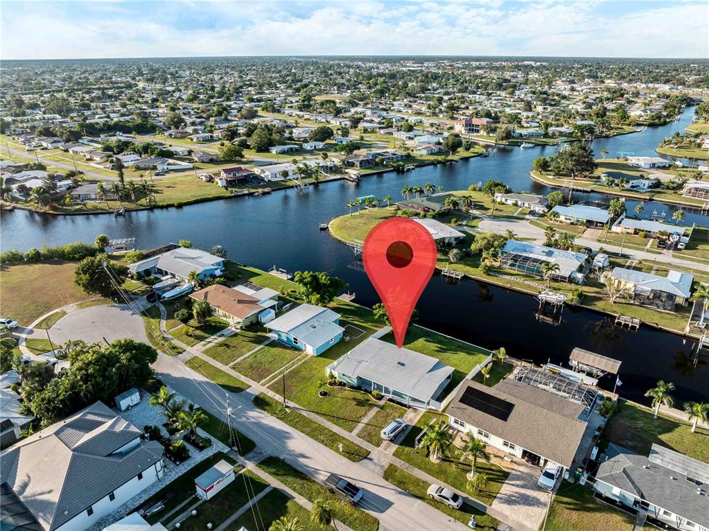 An aerial view shows a single-story house with a canal-front backyard and a red pin — 581 LINDLEY TERRACE, PORT CHARLOTTE, FL
