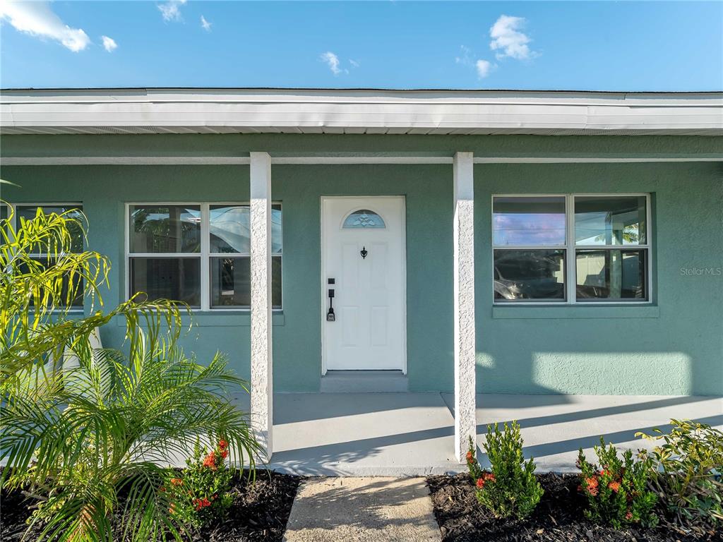 A teal house exterior features a white front door, two windows, and a covered porch — 581 LINDLEY TERRACE, PORT CHARLOTTE, FL