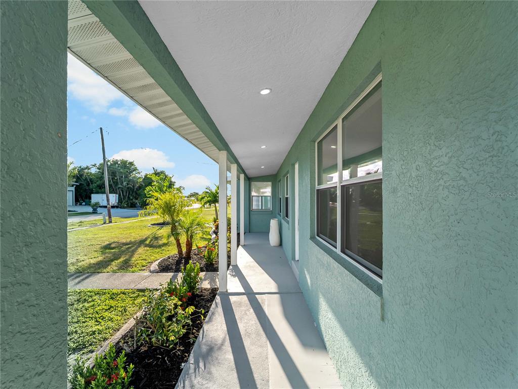 A covered walkway runs along the side of a green stucco house with windows — 581 LINDLEY TERRACE, PORT CHARLOTTE, FL